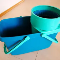 Niebieskie wiadro z zielonym wkładem do mopa obrotowego.